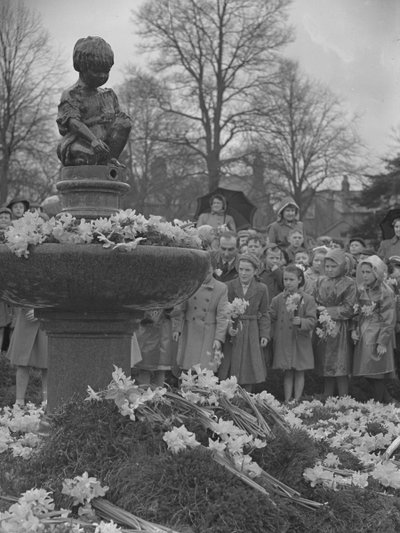 Dzieci umieszczające wiązanki żonkili na fontannie z posągiem na szczycie autorstwa Joseph Hardman