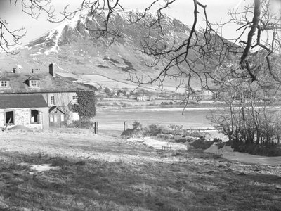 Hotel Anglers w Ennerdale z drzewami na pierwszym planie i zamarzniętym jeziorem i zaśnieżonymi wzgórzami poza nim autorstwa Joseph Hardman