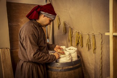 Rekonstrukcja historyczna: Świece i worki pszenicy, żyta i jęczmienia w aptece Diotaiuti, Imola, Włochy, połowa XIV w. (foto) autorstwa Unbekannt Unbekannt