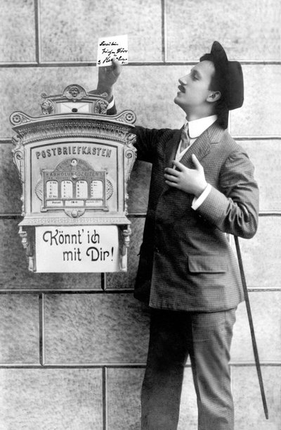 Elegancki mężczyzna w garniturze, kapeluszu i lasce, umieszcza notatkę w skrzynce pocztowej. Niemcy ok. 1920 Zdjęcie historyczne, mężczyzna przy skrzynce na listy, ok. 1920 autorstwa Unbekannt