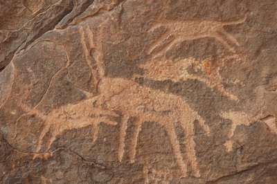 Sztuka naskalna, prehistoria: Rycina przedstawiająca antylopę zaatakowaną przez sforę psów w masywie Uweinat w Egipcie (okres od 8000 do 3000 lat pne). Fotografia autorstwa Unbekannt