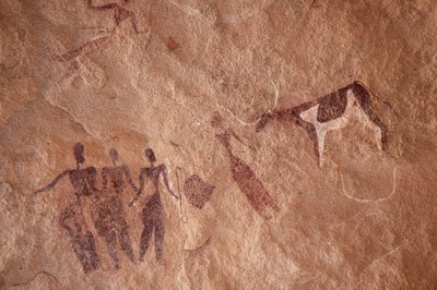 Sztuka naskalna, prehistoria: Malowidło naskalne przedstawiające grupę postaci i dwukolorową krowę z dużymi rogami w ozdobnym schronie, w masywie Uweinat w Egipcie. (Okres od 8000 do 3000 lat pne). Fotografia autorstwa Unbekannt
