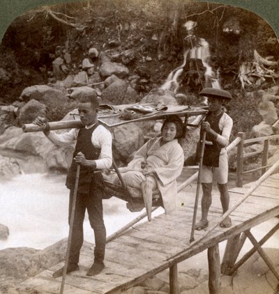 Japonka w górskim krześle yamakago przeprawiająca się przez rwącą rzekę Daiya w pobliżu Nikko w Japonii, autorstwa Underwood and Underwood