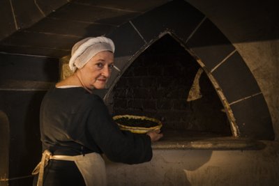 Rekonstrukcja historyczna: Pokojówka wkładająca ciasto do pieca kuchni zamku autorstwa John Ward Dunsmore