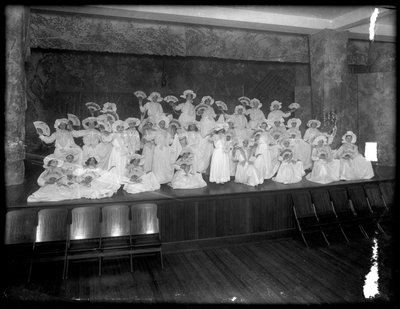 Grupa małych dziewczynek upozowanych na małej scenie trzymających wachlarze, prawdopodobnie w Roman Catholic Orphan Asylum, Kingsbridge, Bronx, ok. 1911 r. autorstwa William Davis Hassler