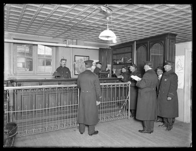 Wnętrze niezidentyfikowanego posterunku policji, widoczni funkcjonariusze i recepcja, ok. 1913-14 autorstwa William Davis Hassler