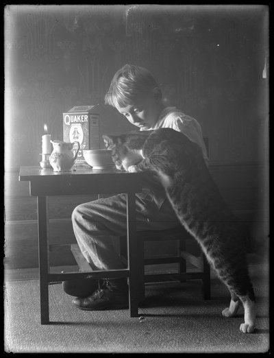 William Grey Hassler i kot Reddy, jedzący płatki ryżu dmuchanego Quaker, ok. 1912 r. autorstwa William Davis Hassler