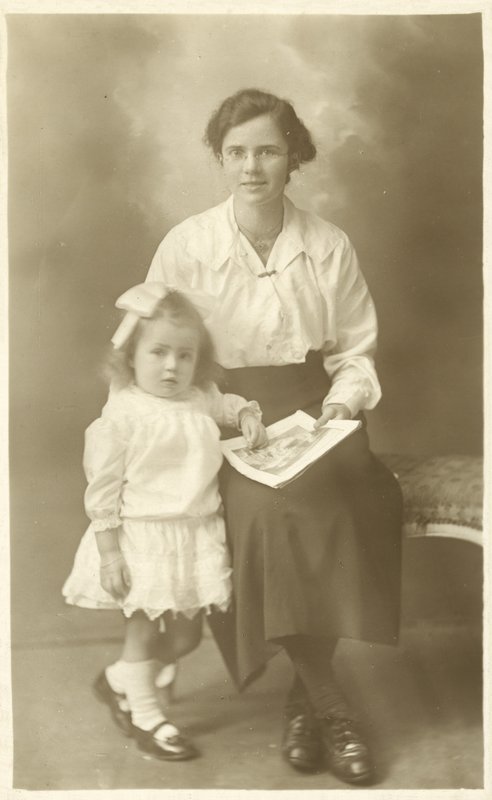 Ładna dziewczyna, mama lub guwernantka, pokazująca zdjęcia małemu dziecku (zdjęcie czarno-białe) autorstwa English Photographer