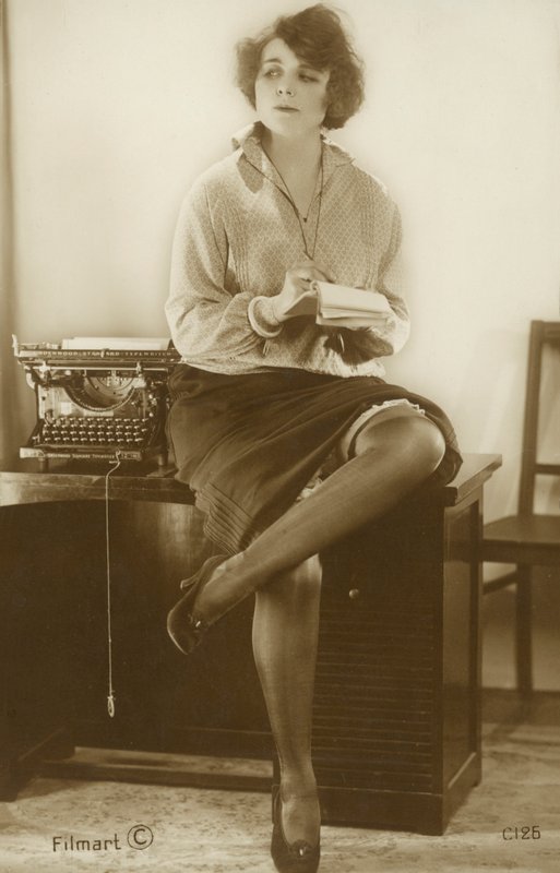 Sekretarka siedząca na biurku (zdjęcie czarno-białe) autorstwa English Photographer
