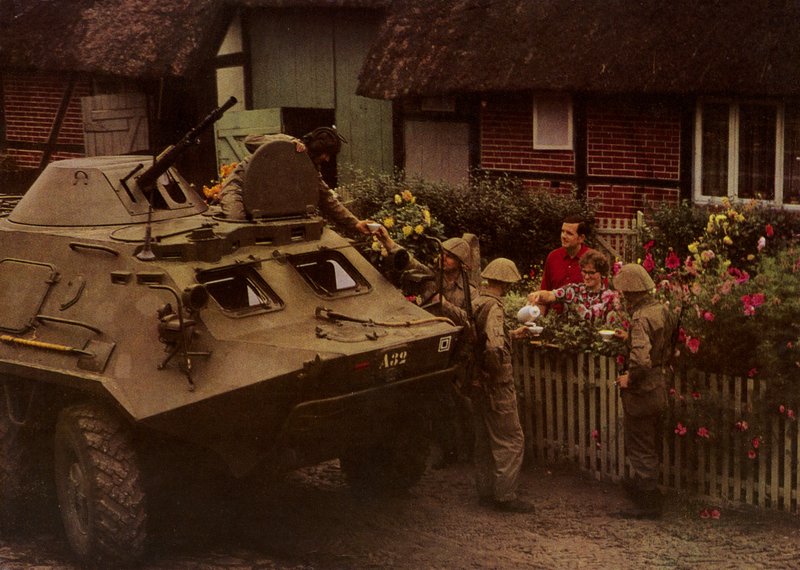 Podczas odpoczynku w marszu żołnierze Narodowego Ludowego Wojska Polskiego są serdecznie witani przez mieszkańców (kolorowe zdjęcie) autorstwa Photographer German