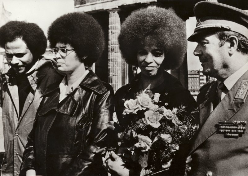 11 września 1972 dzielna amerykańska komunistka i obrończyni praw obywatelskich Angela Davis została serdecznie powitana przez żołnierzy Narodowej Armii Ludowej NRD pod Bramą Brandenburską (zdjęcie czarno-białe) autorstwa Photographer German
