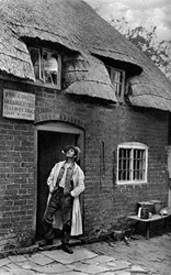 Mężczyzna palący fajkę przed sklepem, Worcestershire, ok. 1922.