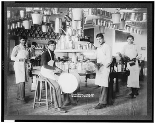 Młodzi rdzenni Amerykanie w warsztacie obróbki metali z wiadrami, baliami, konewkami i innymi metalowymi przedmiotami, Carlisle Indian School, Pensylwania, ok. 1904 (zdjęcie czarno-białe)