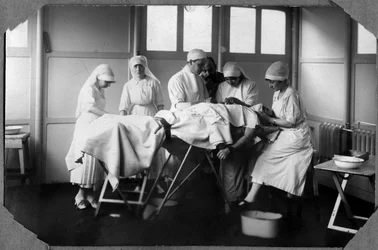 Pierwsza wojna światowa 1914-1918: lekarze i pielęgniarki Czerwonego Krzyża (Therese Pavillou? ) leczą rany żołnierza śpiącego w chloroformie w obozie Couville w Manche, Dolna Normandia (Dolna Normandia), Francja. Fotografia anonimowa