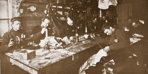 W chacie w środku zimy mężczyźni szyją futra na odzież używaną podczas wiosennych wypraw saniami, wydano w Londynie w 1907