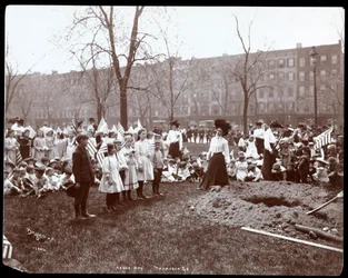 Dorośli i dzieci trzymające flagi stojące wokół nowo wykopanego dołu do sadzenia drzewa w Dzień Arbor w Tompkins Square Park, Nowy Jork, 1904 (srebrny odcisk żelatynowy)