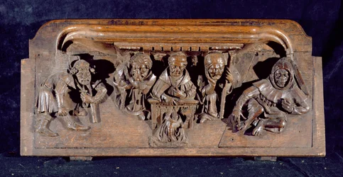 Mizerykorda przedstawiająca naukowca siedzącego przy biurku z panelem, przekazującego napomnienie klęczącemu pokutnikowi, New College Chapel, Oksford, koniec XIV wieku (drewno)