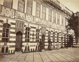 Dziedziniec domu żydowskiego w Stambouli w Syrii. W pobliżu ścian budynku pokazano trzech domowników