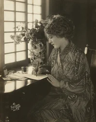 Mary Pickford, ubrana w kimono, pisząca przy biurku, ok. 1918 (zdjęcie czarno-białe)