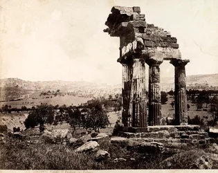 Widok na pozostałe cztery kolumny podtrzymujące belkowanie świątyni Kastora i Polluksa w Valle dei Templi, Agrigento. W tle widoczna panorama miasta