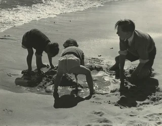 Trójka dzieci bawiących się piaskiem na plaży.