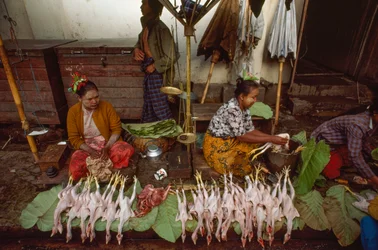 Sprzedawcy żywności z twarzami ozdobionymi thanaką, sproszkowaną korą drzewną. Taunggyi, Birma.