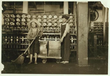 12-letni doffer Ronald Webb i 7-letni Frank Robinson, syn szefa sali karcianej, który zamiata i zdejmuje (oczyszcza pełne szpulki) w Roanoke Cotton Mills, Virginia, 1911