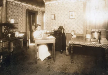 Kobieta wkładająca włosie do szczoteczek do zębów w swojej kuchni, ok. 1912 r.