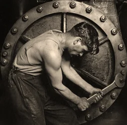 zbliżenie mechanika elektrowni pracującego na pompie parowej ok. 1920 r. (zdjęcie)