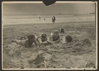 [Dzieci leżące w piasku na plaży]