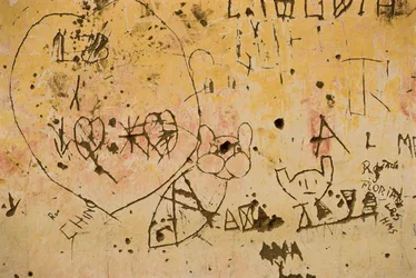 Grafitti wyryte na starej zewnętrznej ścianie gipsowej.
