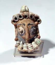Starożytność orientalna: amulet w kształcie męskiej głowy znaleziony w grobowcu w Kartaginie. Okres punicki, ziemia lakierowana. 400-300 pne. Paryż, Luwr