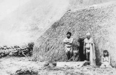 Stara kobieta bijąca tapę przed domem z trawy pili, Kalaupapa, Hawaje, XIX wiek