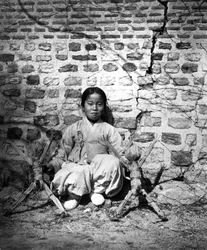Dziecko siedzące pod ścianą, Korea, ok. 1900