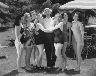 Hollywood, Kalifornia: ok. 1935 Siedem młodych kobiet w strojach kąpielowych walczy o względy samotnego mężczyzny. (zdjęcie czarno-białe)