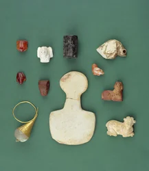 Kolekcja obiektów ze wschodniego wybrzeża Morza Śródziemnego, w tym amulet sępa sumeryjskiego, akadyjska serpentynowa pieczęć i mezopotamska żaba karneolowa, z lat 3300-2000 p.n.e.