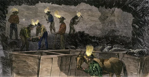 Górnicy kopiący kopalnię i ładujący węgiel do małych wagoników opalanych mułami w Pensylwanii. Kolorowa rycina z 1860 roku.