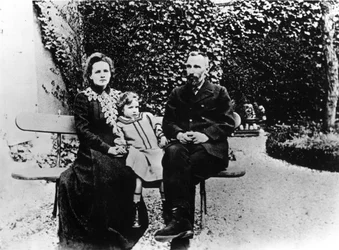 Pierre (1859-1906) i Marie Curie (1867-1934) siedzą na ławce w ogrodzie.