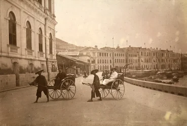 Dwóch mężczyzn przewożonych rikszą w Hongkongu.