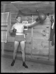 Angielski bokser William Thomas Wells (Bombardier Billy Wells), pozujący w dresach treningowych z torbą, ok. 1911.