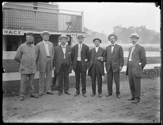 Siedmiu niezidentyfikowanych mężczyzn pozuje w pobliżu rzeki lub jeziora, ok. 1910 r