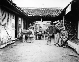 Wędrowni fryzjerzy w wiejskim domu, Chiny, ok. 1875 r